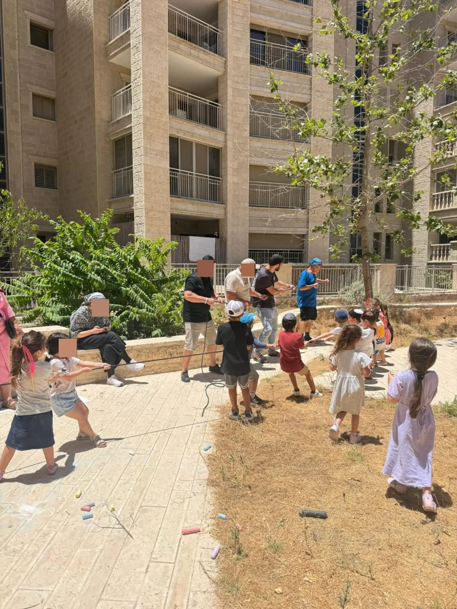 ילדי הגן משחקים משיכת חבל בחצר במהלך מסיבת הסיום