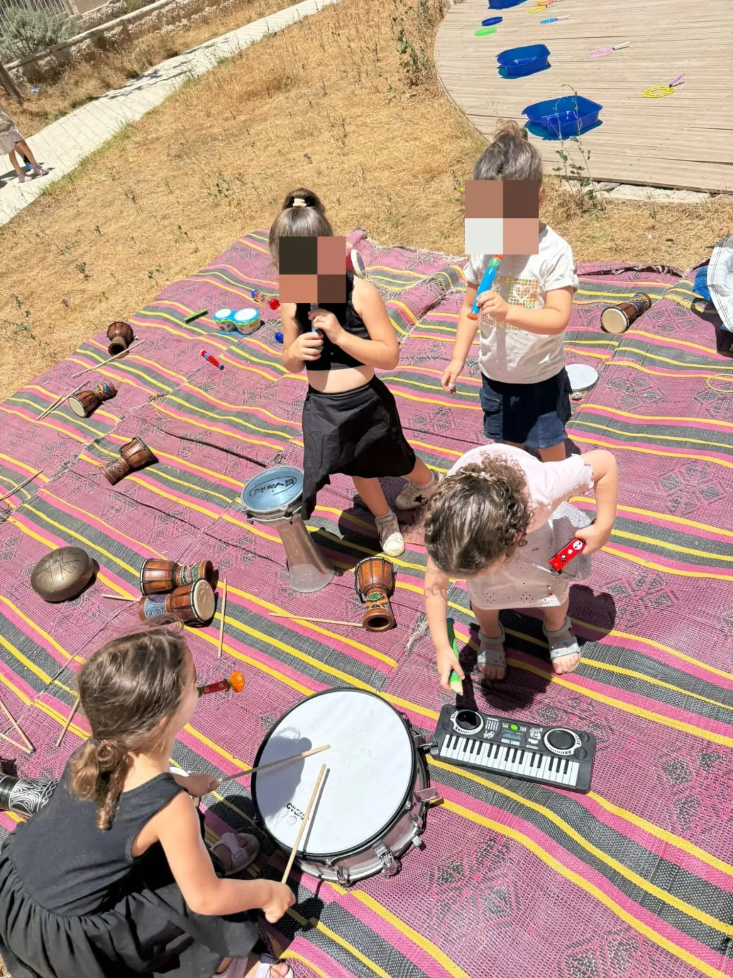 תחנת כלי נגינה — ילדים משחקים בתופים ופסנתר במסיבת הגן