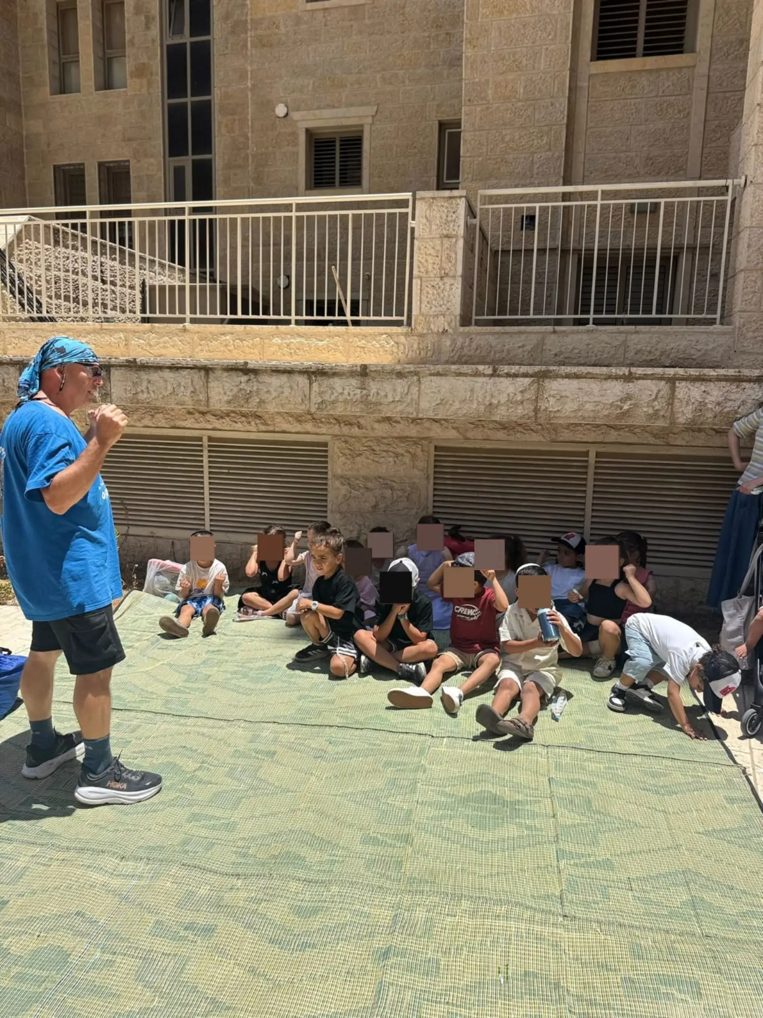 אמנון מספר סיפור לילדי הגן היושבים במעגל על מזרן